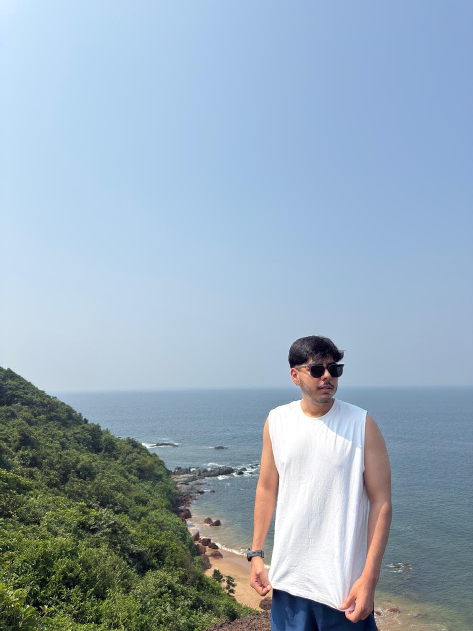 Kristan Dharel on a green hillside above the sea